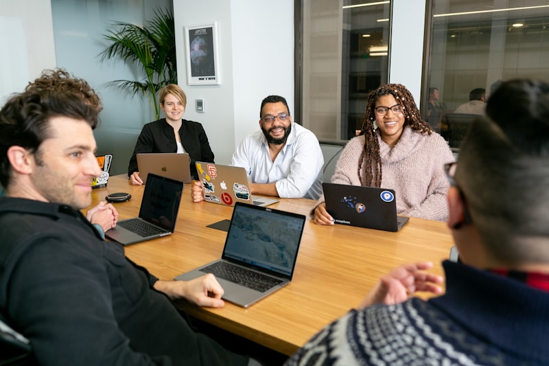 Team collaborating around a table with laptops